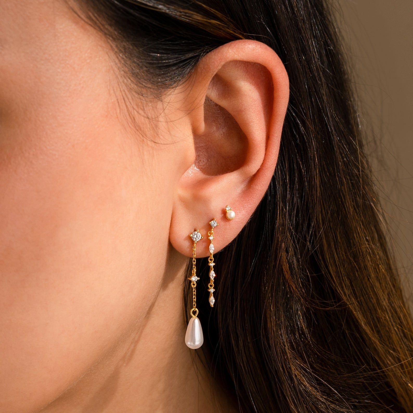 Close-up of a woman's ear wearing Diamond Pearl Chain Earrings, featuring a pearl teardrop charm and elegant diamond studs.