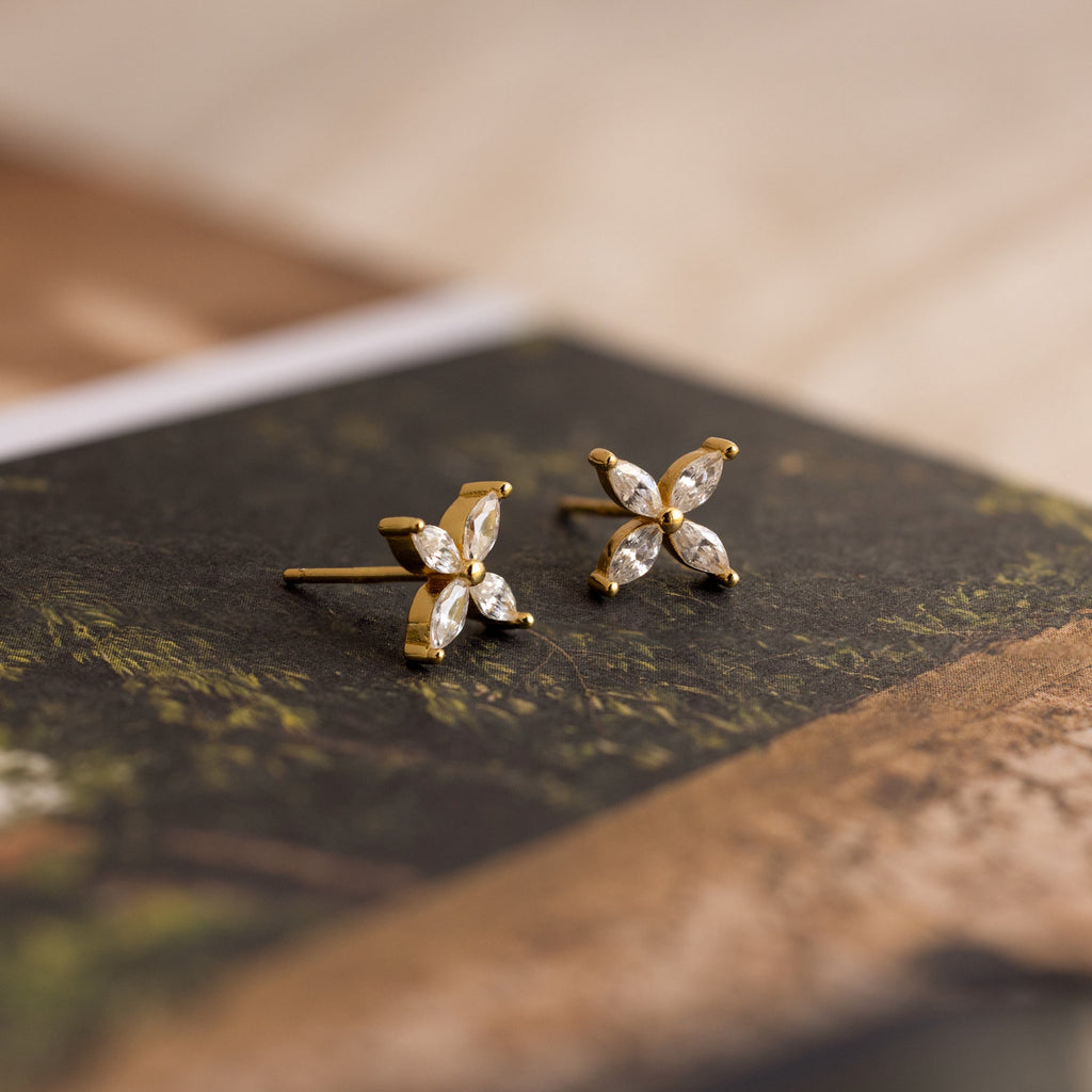 Marquise Diamond Flower Studs with four leaf-shaped clear stones in a floral design, elegantly displayed on a book—perfect as floral earrings and exquisite wedding jewelry.