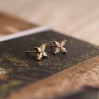 Marquise Diamond Flower Studs with four leaf-shaped clear stones in a floral design, elegantly displayed on a book—perfect as floral earrings and exquisite wedding jewelry.