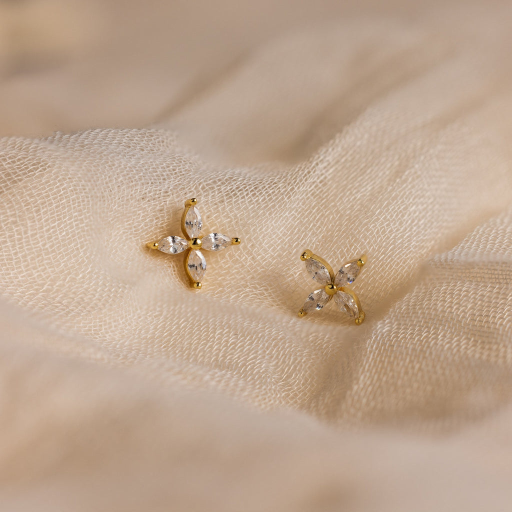 Marquise Diamond Flower Studs featuring gold and crystal details rest elegantly on cream-colored fabric—ideal floral earrings for weddings or special occasions.