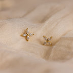 Marquise Diamond Flower Studs featuring gold and crystal details rest elegantly on cream-colored fabric—ideal floral earrings for weddings or special occasions.