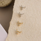 Four Trio Floral Marquise Stud earrings in silver and gold finishes, displayed on textured beige paper.
