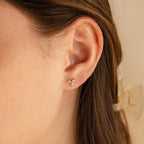 Close-up of a woman's ear wearing Trio Floral Marquise Studs, small gold earrings with three marquise stones arranged in a flower shape.