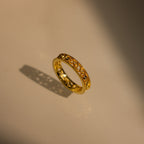 The Filigree Flower Ring, featuring a vintage-inspired design and gold band, casts a delicate shadow on a smooth, light-colored surface.