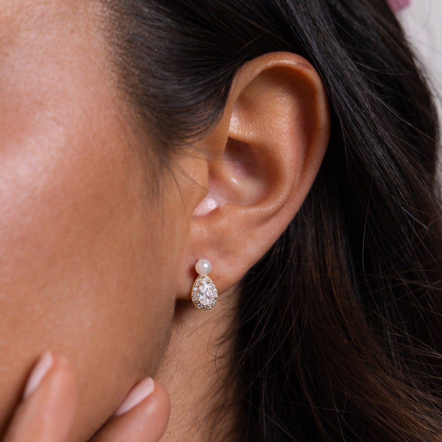 A close-up of a woman's ear adorned with elegant Pearl Diamond Teardrop Studs.