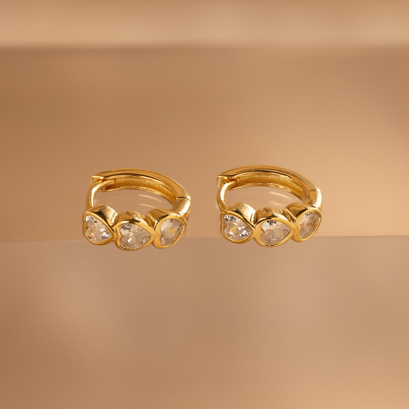 Diamond Bezel Heart Huggies: Gold huggie earrings featuring sparkling diamonds in a delicate heart-cut design.