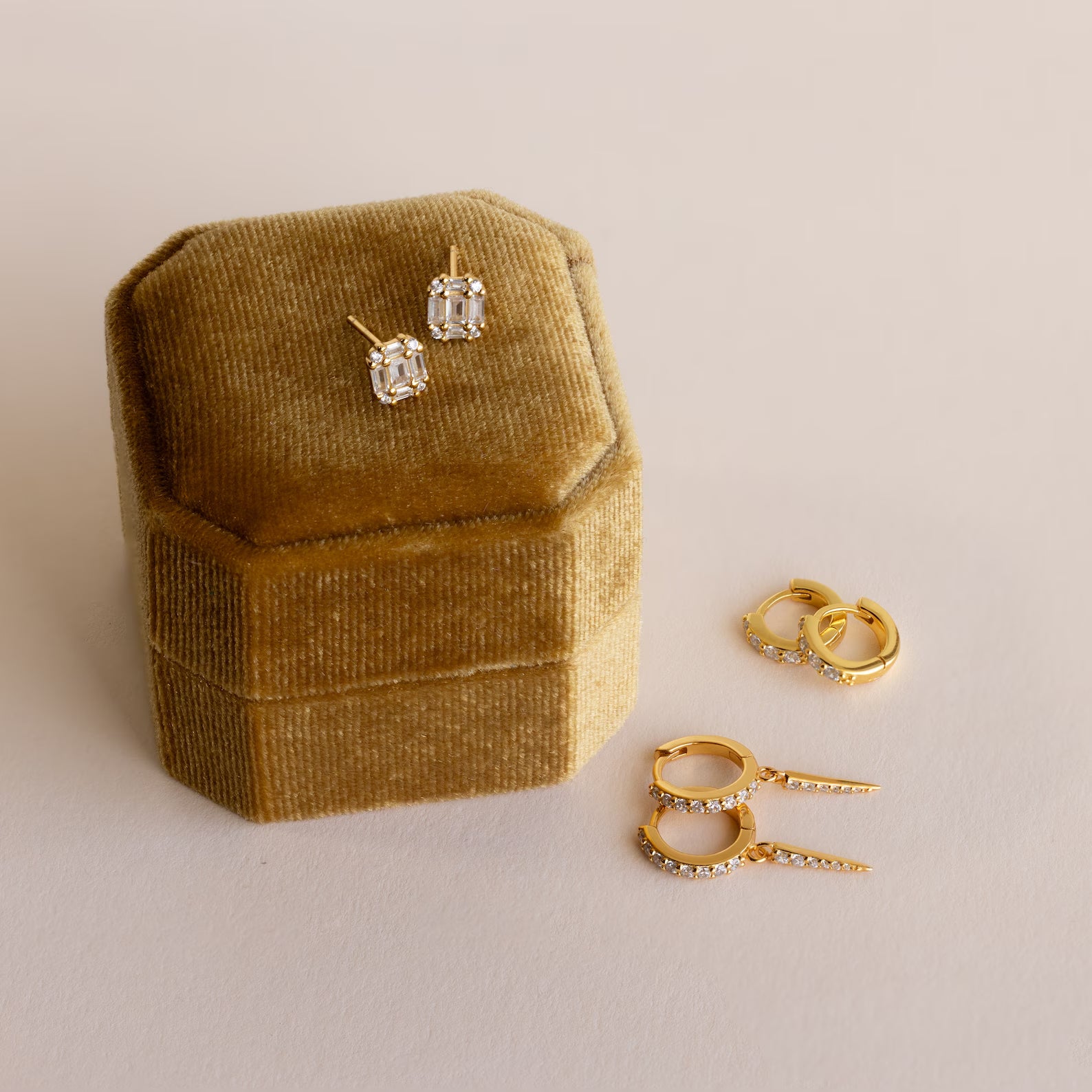 Gold and diamond earrings are elegantly displayed on and beside the Mystery Earrings Box, set against a light background.