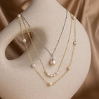 The Mystery Necklace Box from our jewelry collection features three layered pearl necklaces displayed on a smooth, curved beige mannequin against a satin background.