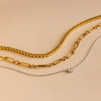 Three necklaces from the Mystery Necklace Box on a beige background: two gold chains and one delicate silver chain with a small pendant—ideal for your jewelry collection or as a special surprise.