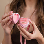 A woman holds an open Pink Velvet Heart Ring Box, displaying two gold rings inside.