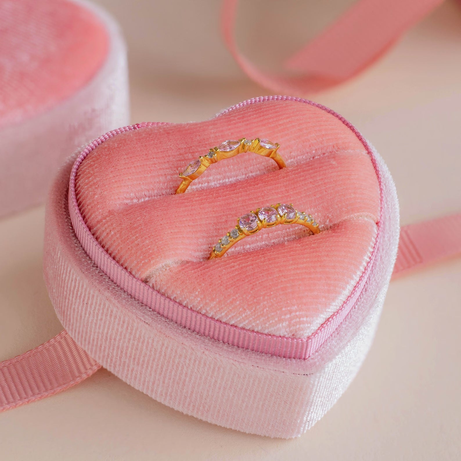 Two gold rings with gemstones sit elegantly in the Pink Velvet Heart Ring Box, making it an ideal display for coquette style or a charming addition to your jewelry collection.