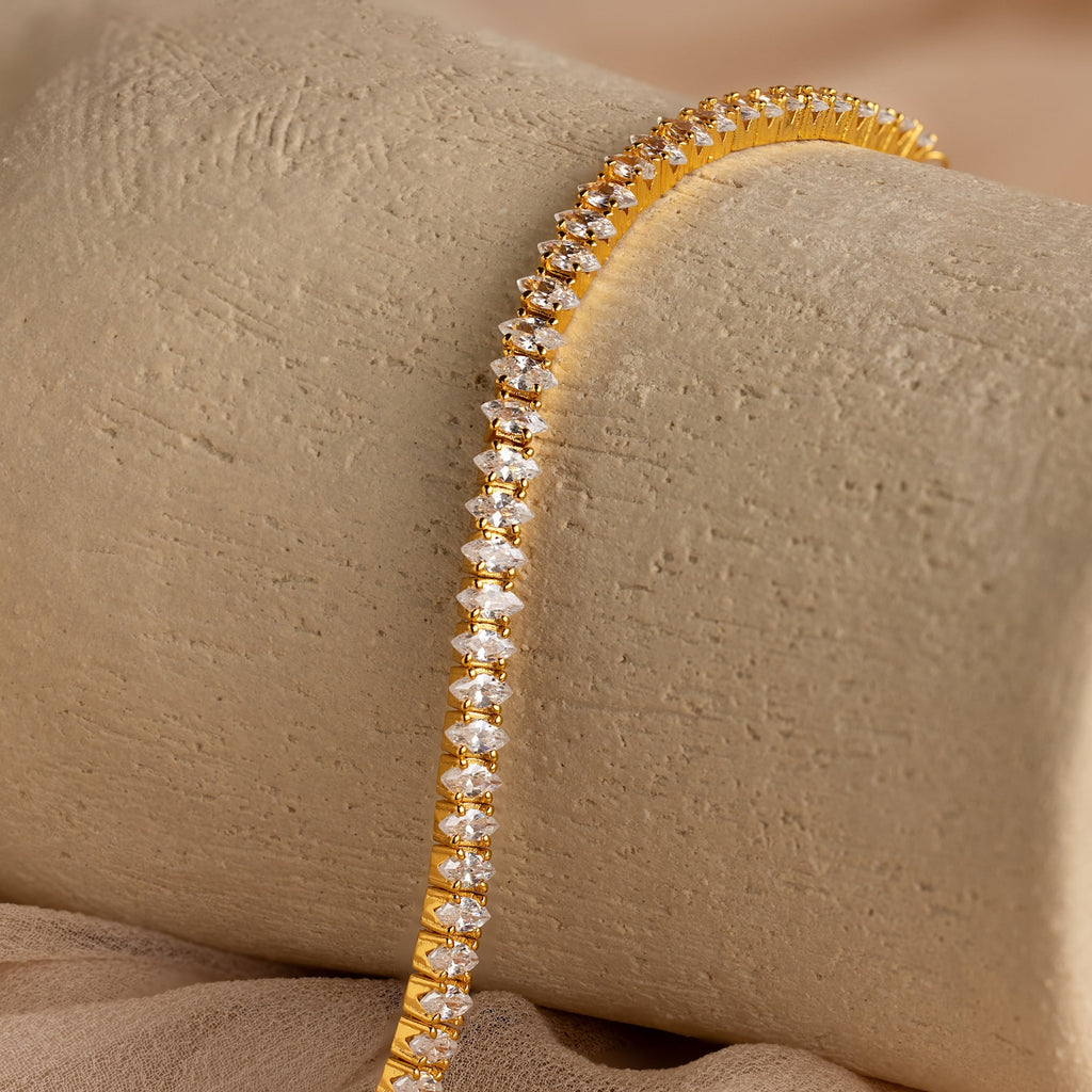Detailed view of the Marquise Diamond Tennis Bracelet draped over a neutral textured surface, showcasing the brilliance of the marquise-cut stones.