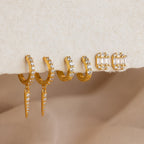 Three pairs of gold earrings with small clear stones rest on a soft, beige surface—ideal for adding to your Mystery Earrings Box.