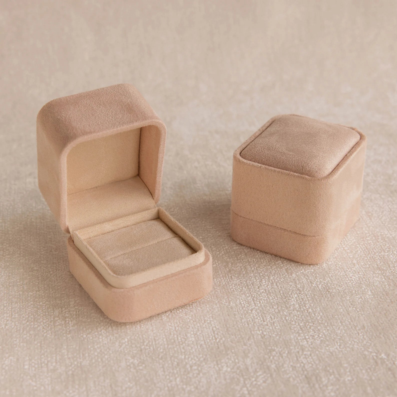 A pink suede ring box, shown both open and closed on a light textured surface, is an ideal pick for fans of minimalist design.