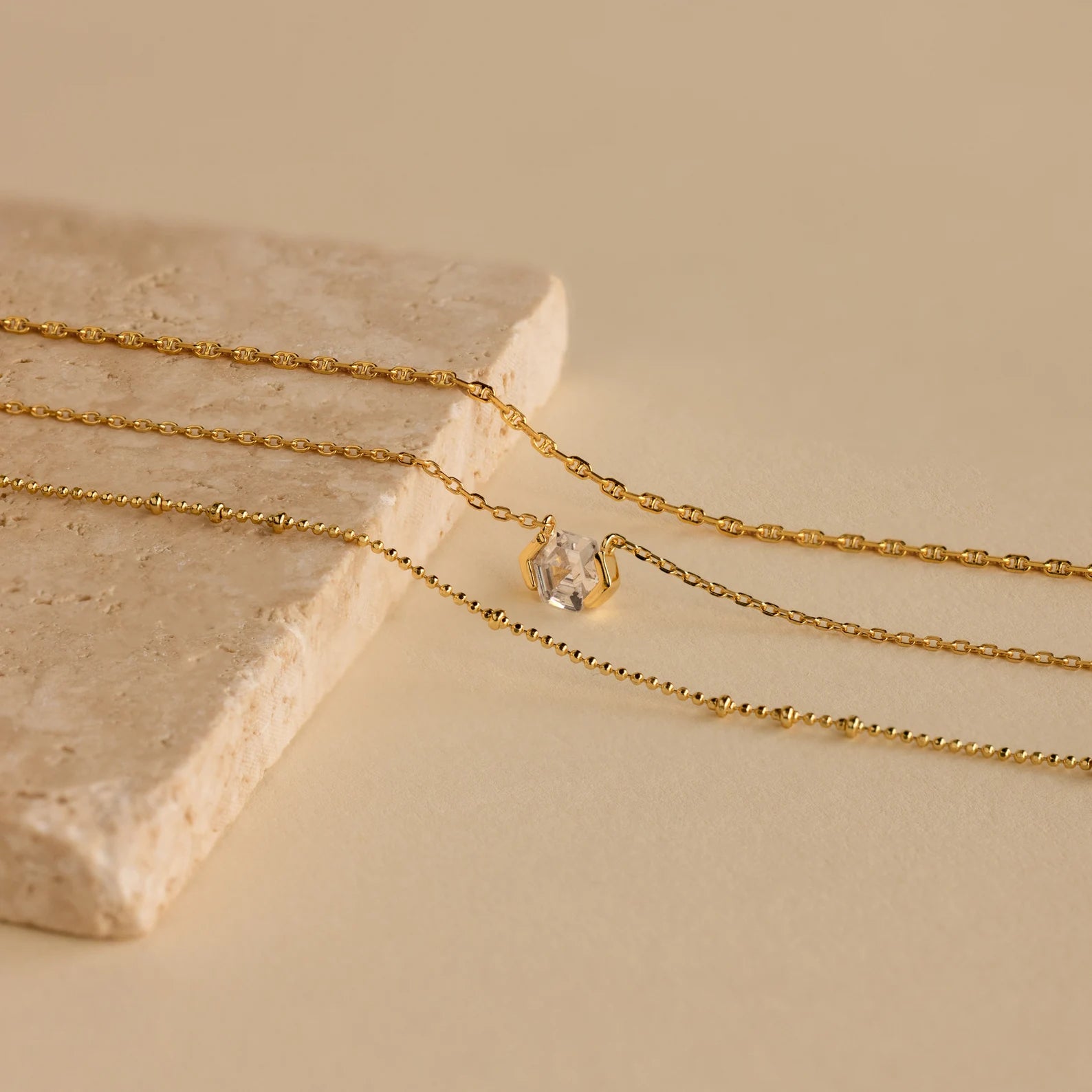 The Skinny Mariner Chain Necklace, elegantly displayed on a beige stone surface, is perfect for everyday wear or layering to achieve a chic look.