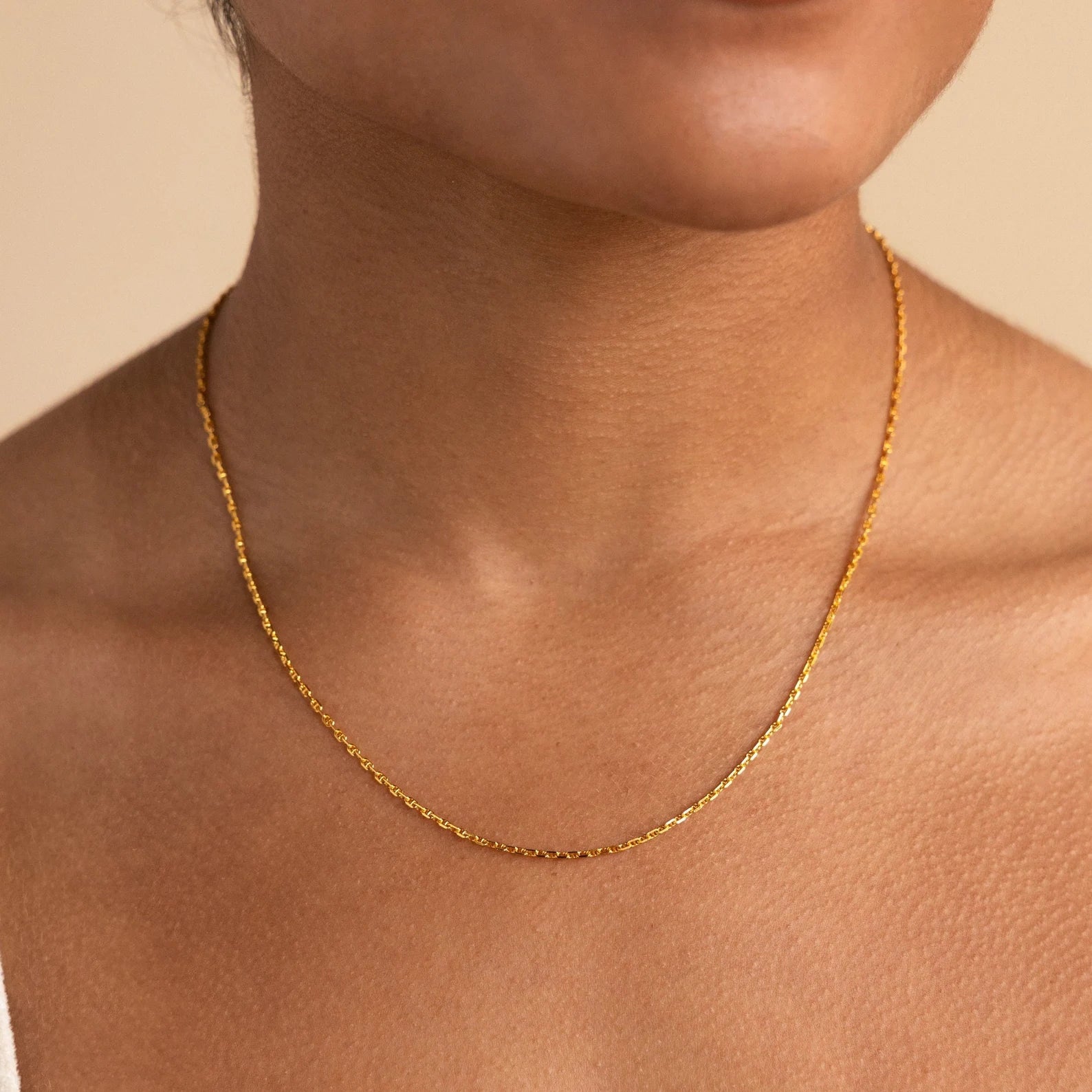 A close-up shows someone wearing the Skinny Mariner Chain Necklace, a delicate piece that's perfect for everyday wear.