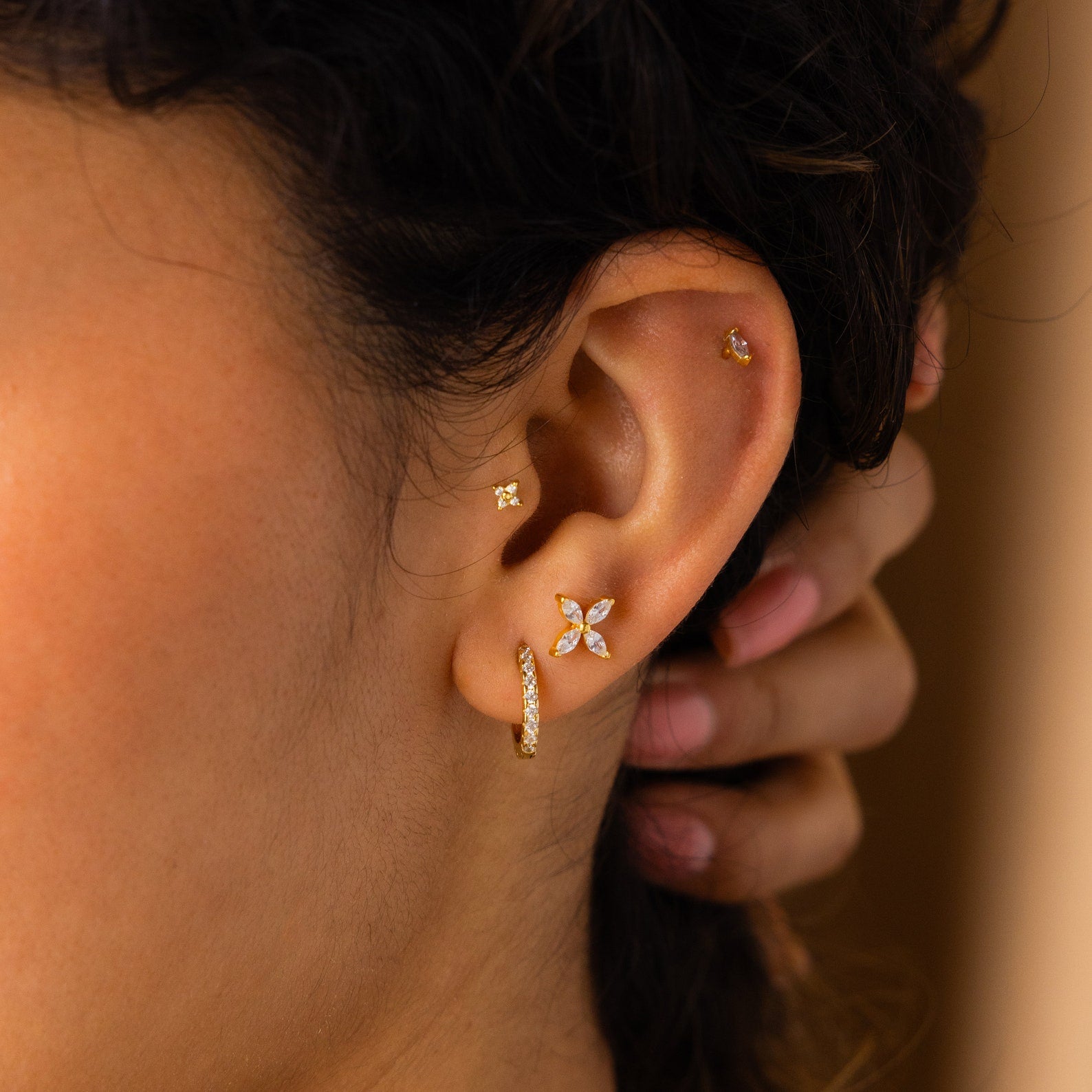 A close-up of an ear adorned with gold and diamond Birthstone Flower Studs and a small hoop, highlighting the elegance of personalized earrings.