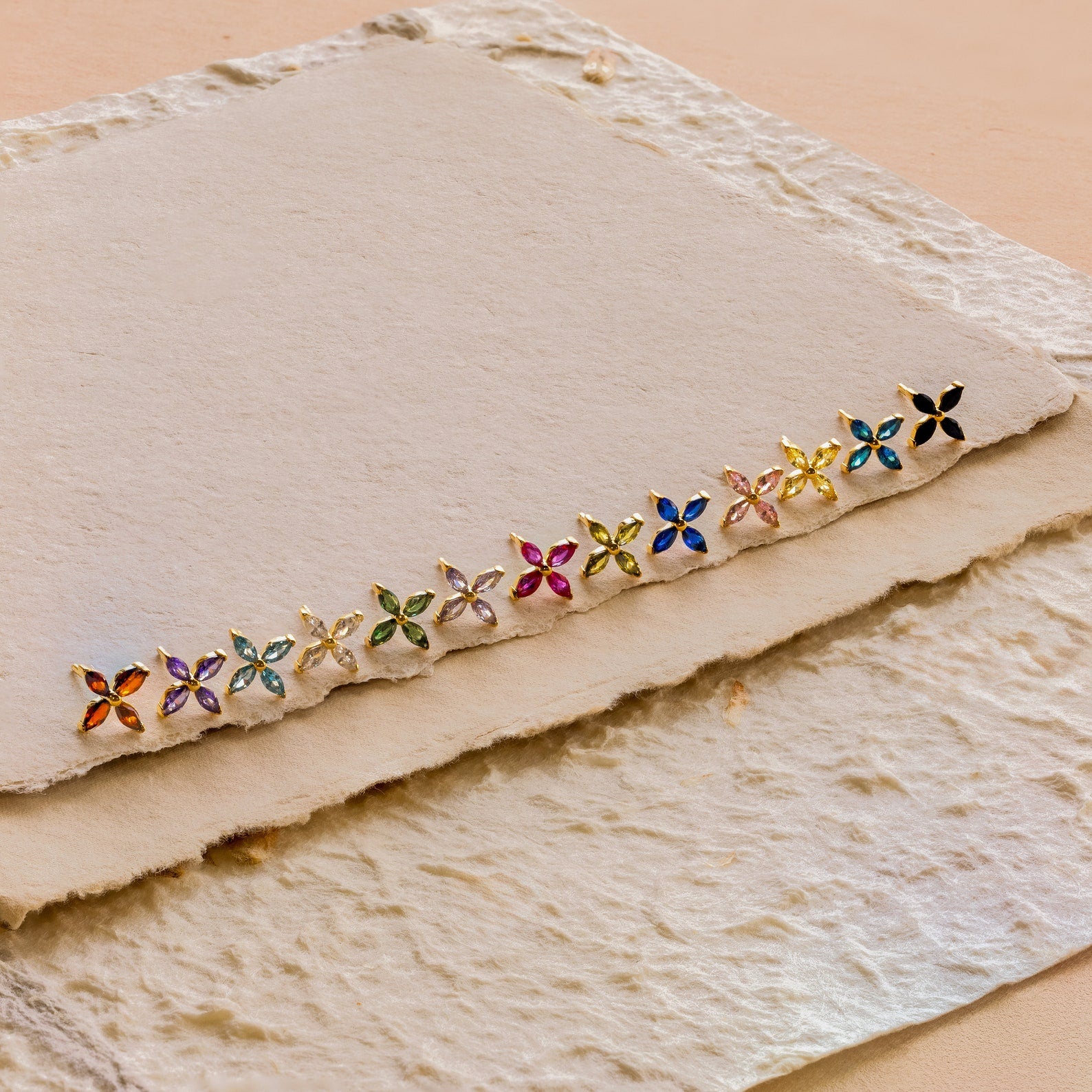 Birthstone Flower Studs displayed on textured, cream handmade paper, ideal for adding a personalized touch to any outfit.