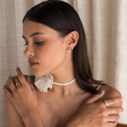Model showcases Diamond Ribbon Bow Huggies paired with Diamond Drop Earrings, a Gold Dome Ring, and a Curved Diamond Ring. 