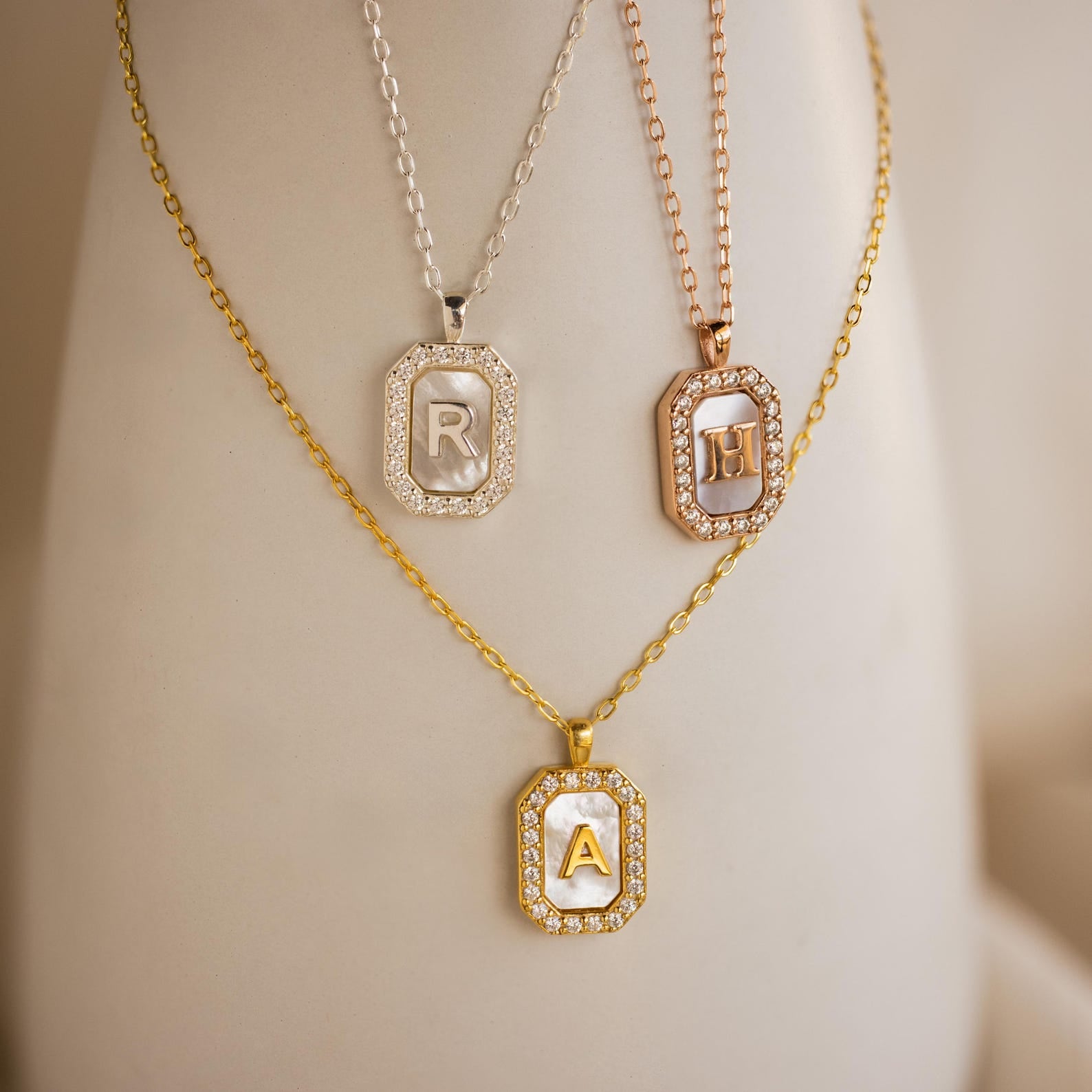 The Pave Gemstone Initial Necklace comes in R, H, and A pendants on gold, silver, or rose gold chains, each accented with sparkling Pavé gemstones.