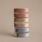 Three Round Velvet Jewelry Cases in pink, beige, and gray—each a minimalist Round Velvet Jewelry Case with gold zippers—are stacked to create an elegant travel jewelry organizer.