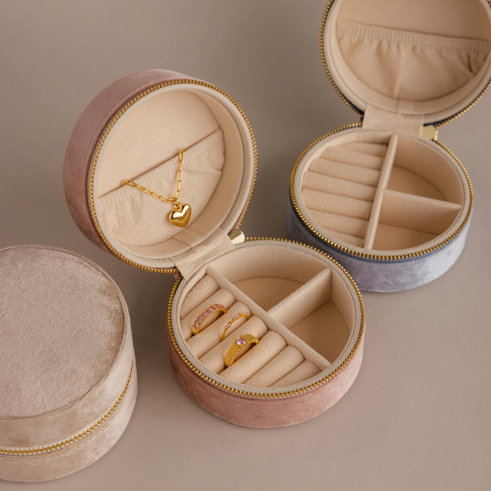 Two Round Velvet Jewelry Cases display gold rings and a necklace on a beige surface, ideal as minimalist jewelry boxes or travel organizers.