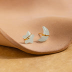 Aquamarine Moon & Star Studs shaped like a star and crescent moon rest on a textured beige surface—perfect dainty stud earrings for adding everyday sparkle.