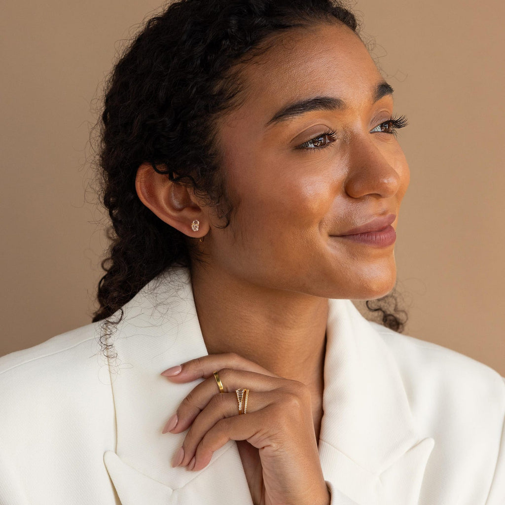 Woman in a white blazer, smiling and looking to the side, wears gold rings and Herkimer Diamond Threaders for a chic yet relaxed look.