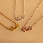 Three Essential Vote Necklaces in gold, silver, and rose gold rest on a beige surface—a meaningful and inspiring gift for voters or anyone who loves a symbolic voting necklace.