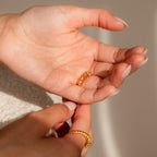 A hand holds a gold ring while another adjusts it, showing how the Ring Size Adjuster ensures a perfect fit for loose rings.