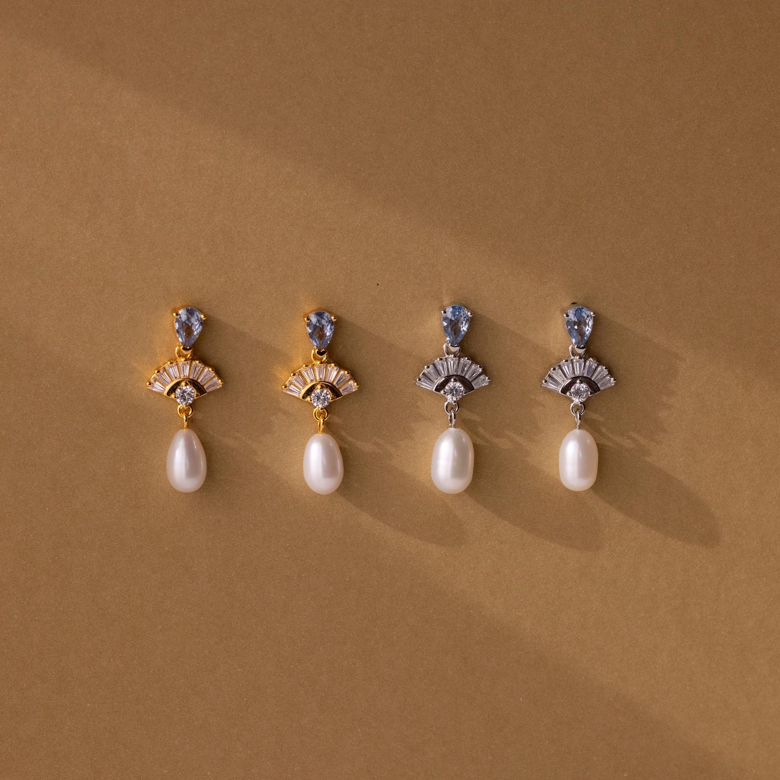 Four pairs of Aquamarine Pearl Drop Earrings—two gold, two silver—evoke vintage glamour, making perfect wedding jewelry and displayed elegantly on a brown background.