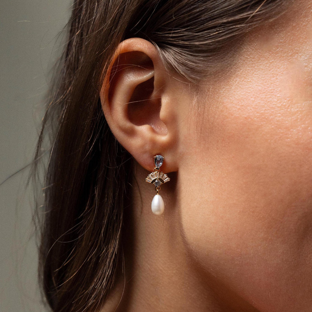 A close-up of a woman's ear showcases Aquamarine Pearl Drop Earrings, highlighting their vintage glamour—perfect as wedding jewelry.