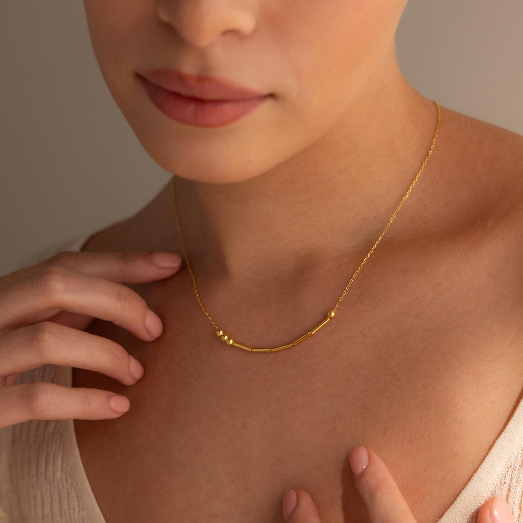 A woman wears the Essential Vote Necklace, gently touching her collarbone—a meaningful and beautiful gift for voters.