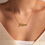 Worn with a cream top, the Elegant Birthstone Name Necklace features a gold cursive name pendant that highlights the charm of personalized jewelry.
