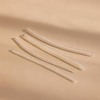 Four transparent, coiled Ring Size Adjusters are arranged diagonally on a beige surface under soft lighting.