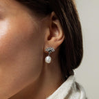 Close-up of a woman wearing Art Deco Pearl Drop Earrings, featuring a silver fan design with a dangling pearl for timeless elegance.