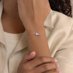 A person wears the Toi et Moi Birthstone Bracelet, which features a slim silver band and a customizable rectangular birthstone gem on their wrist.
