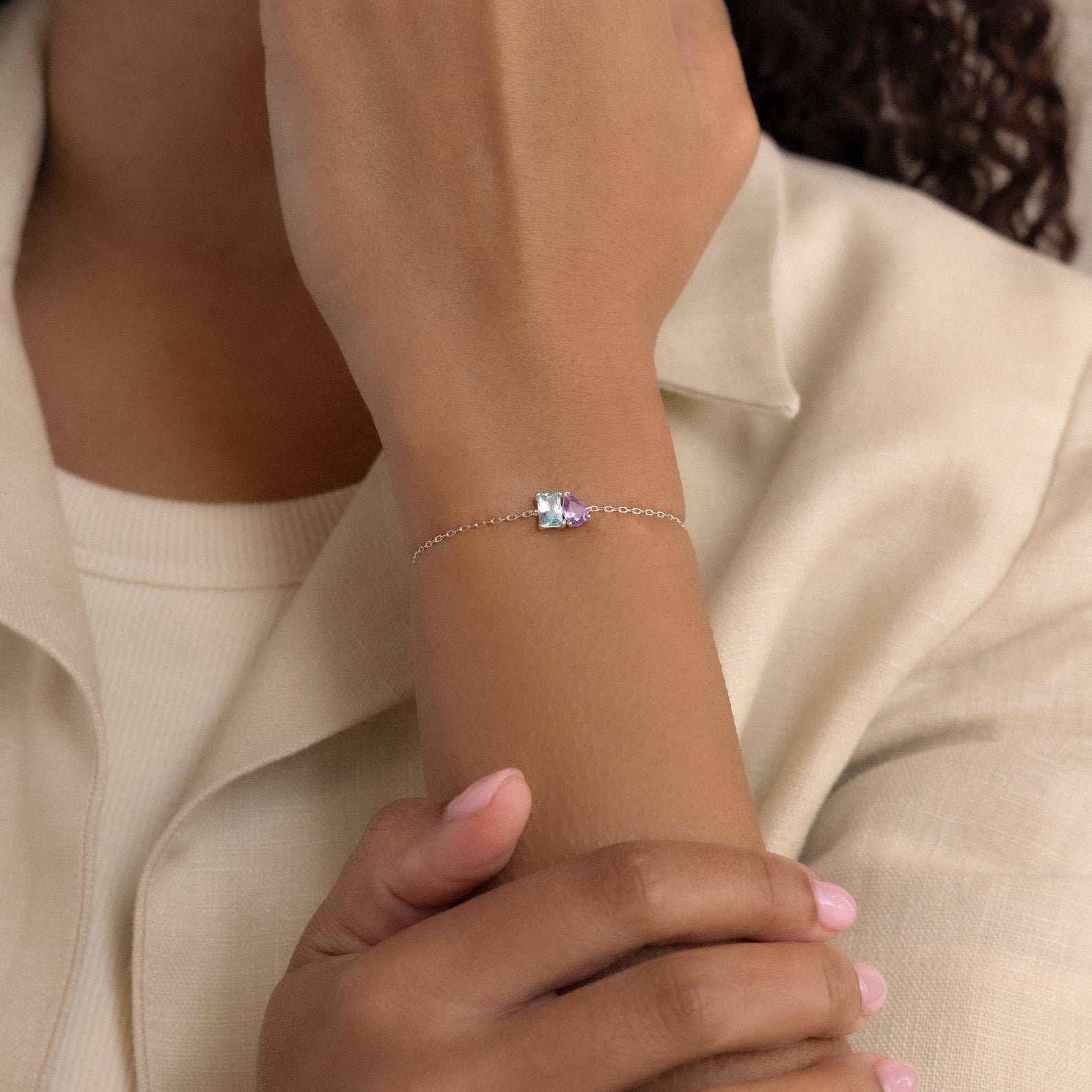 A person wears the Toi et Moi Birthstone Bracelet, which features a slim silver band and a customizable rectangular birthstone gem on their wrist.