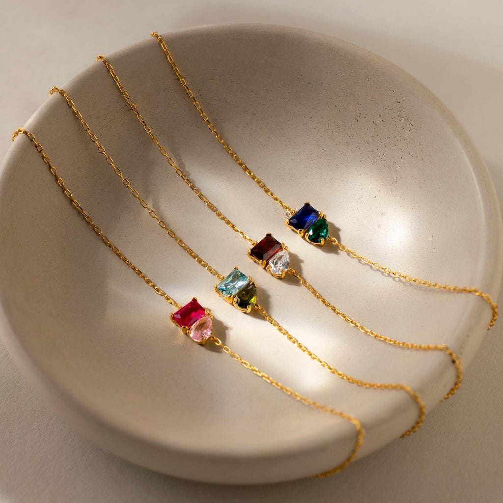Four Toi et Moi Birthstone Bracelets, featuring customizable colorful gemstones, are displayed in a cream ceramic bowl.