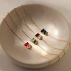 Four Toi et Moi Birthstone Bracelets, featuring customizable colorful gemstones, are displayed in a cream ceramic bowl.