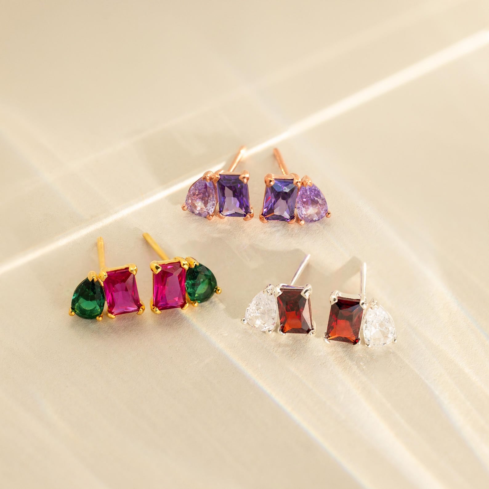 Three pairs of Toi et Moi Birthstone Earrings shine on a reflective surface.