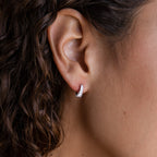 Close-up of a woman's ear with curly hair, wearing the Art Deco Diamond Earrings from the Sterling Silver Earrings & Ring Set for a touch of vintage elegance.