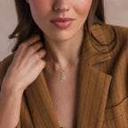 A woman in a brown pinstripe blazer wears the Large Pave Initial Necklace, featuring a sparkling silver 'A' pendant adorned with diamonds.