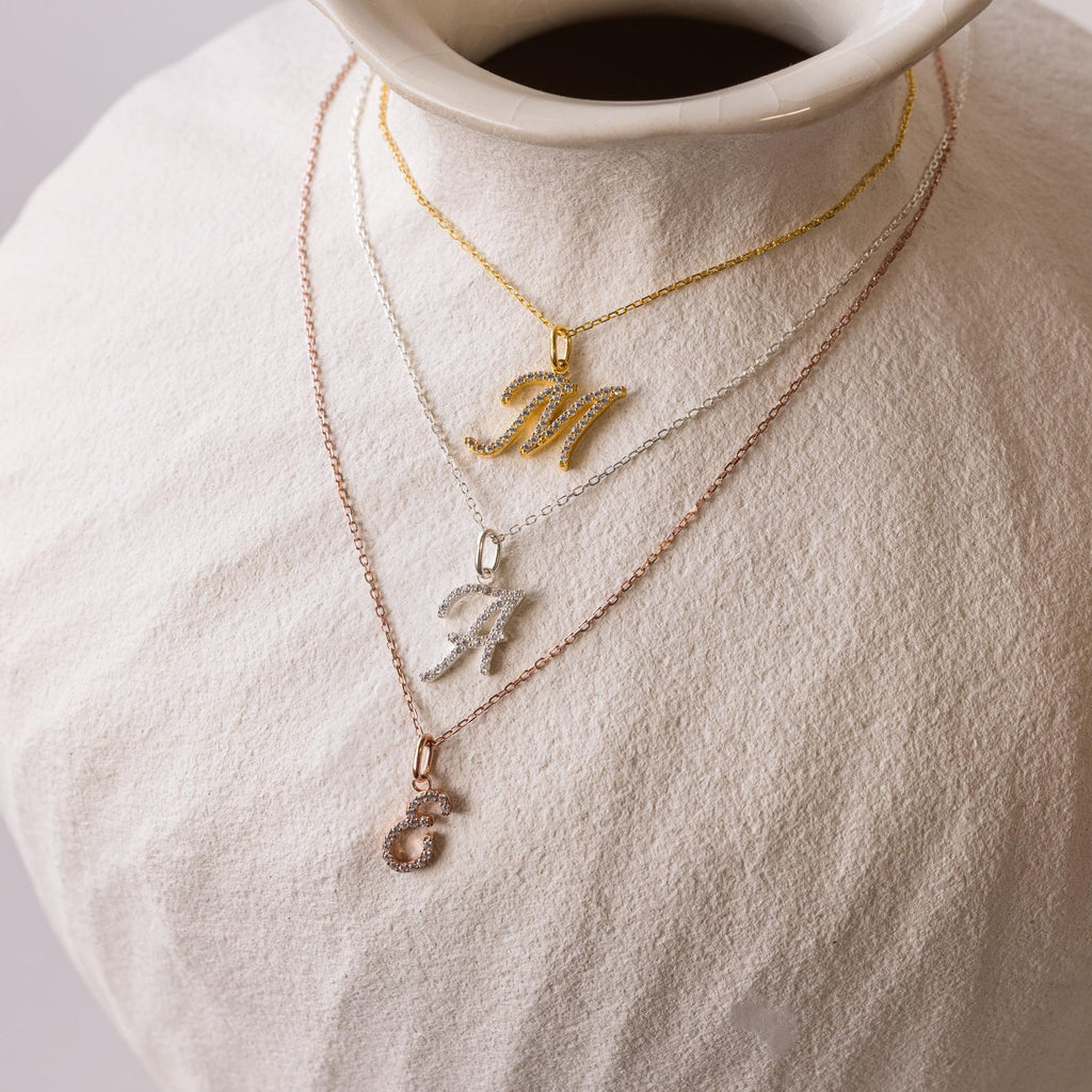 Three Large Pave Initial Necklaces in gold, silver, and rose gold, each with a jeweled initial charm—M, A, or S—sparkle with diamond stones for a stylish layered look.