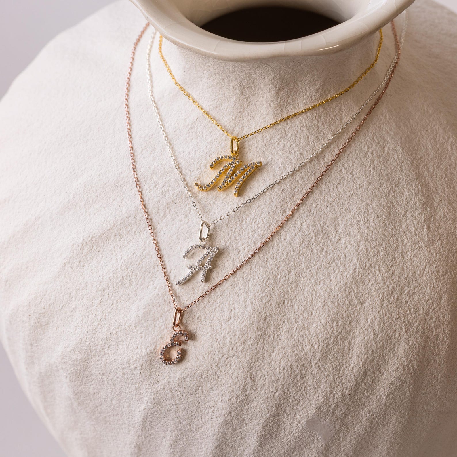 Three Large Pave Initial Necklaces in gold, silver, and rose gold, each with a jeweled initial charm—M, A, or S—sparkle with diamond stones for a stylish layered look.