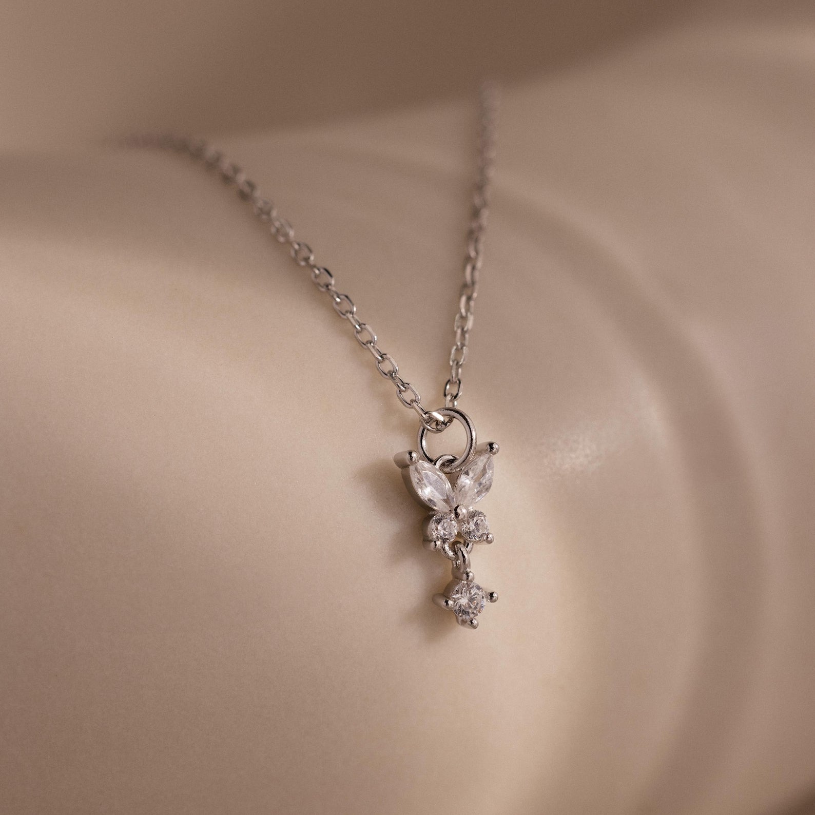 Close-up of the Diamond Butterfly Drop Jewelry Set in Sterling Silver, featuring a delicate diamond butterfly pendant resting gracefully on smooth, light-colored skin.