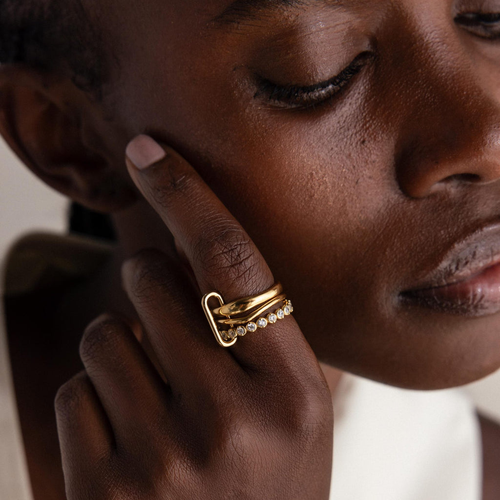 A person with closed eyes touches their face, showcasing the Multipurpose Mixed Metal Clasp Set—an elegant accessory perfect for stacking and adding sophisticated style to any look.