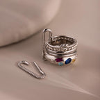 Five silver rings adorned with vibrant gemstones are stacked on a paperclip, next to a jeweled paperclip—perfect for creative jewelry styling or pairing with our Multipurpose Pave Link Clasp Set.