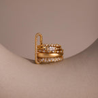 The Multipurpose Pave Link Clasp Set in 18K Gold shines atop a smooth, curved beige surface, highlighting its elegant design against a neutral background.