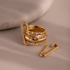 Stacked 18K gold rings with embedded diamonds sit beside the Multipurpose Pave Link Clasp Set in 18K Gold, creating an elegant jewelry styling display on a beige surface.